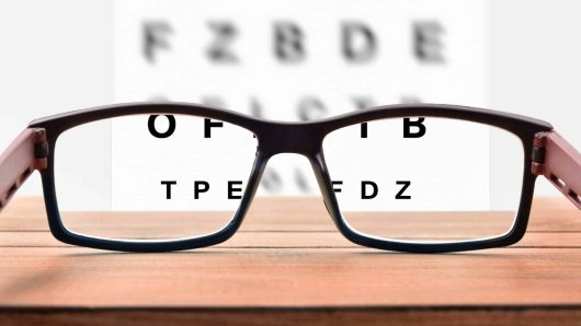 Concept of eye revision with sheet with letters and correction glasses. Front view. Horizontal composition